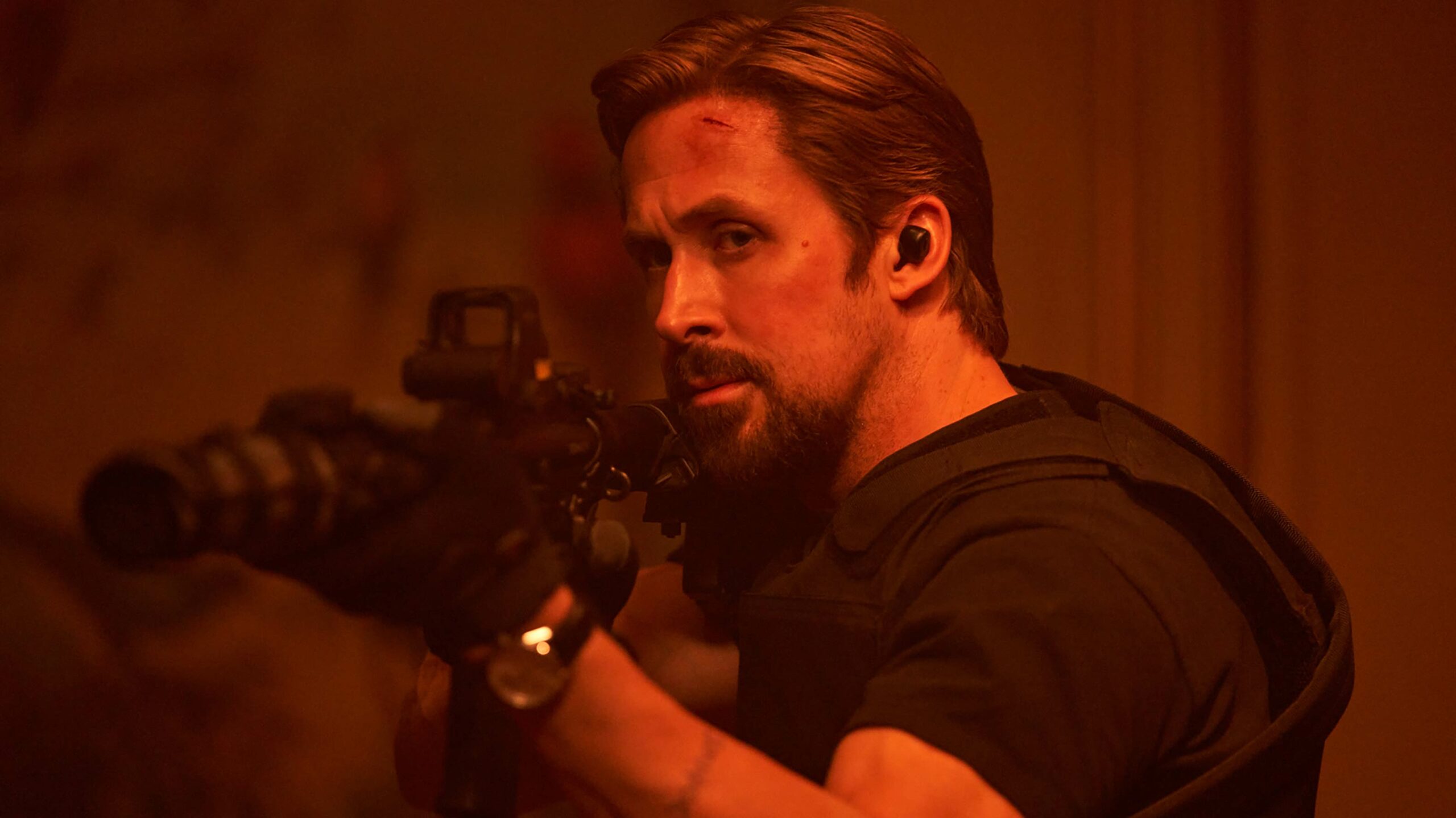A bearded Ryan Gosling aims a rifle in the Netflix film, The Gray Man