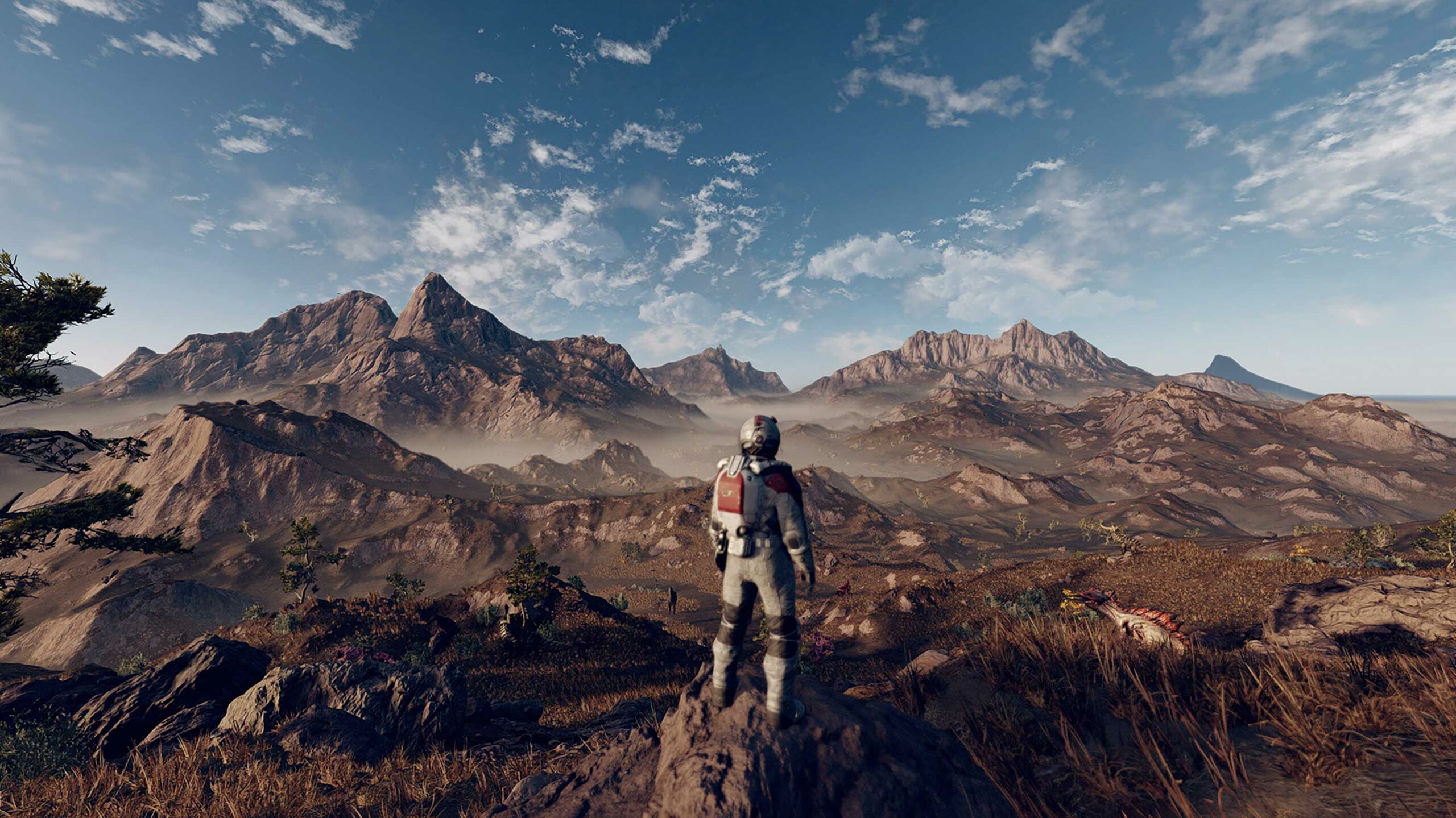 Screenshot from Xbox's Starfield. A man in a space suit stares out onto a planet's vast and empty surface, with many hills visible in the distance.