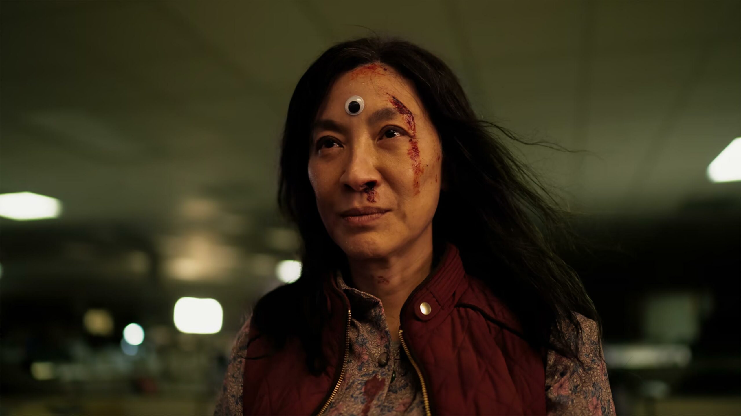 Michelle Yeoh with a googley-eye on her head in Everything Everywhere All At Once